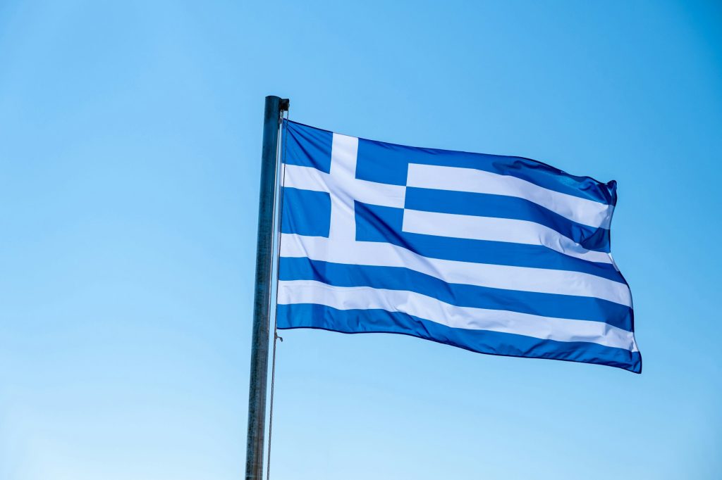 Greek flag waving against blue sky background.